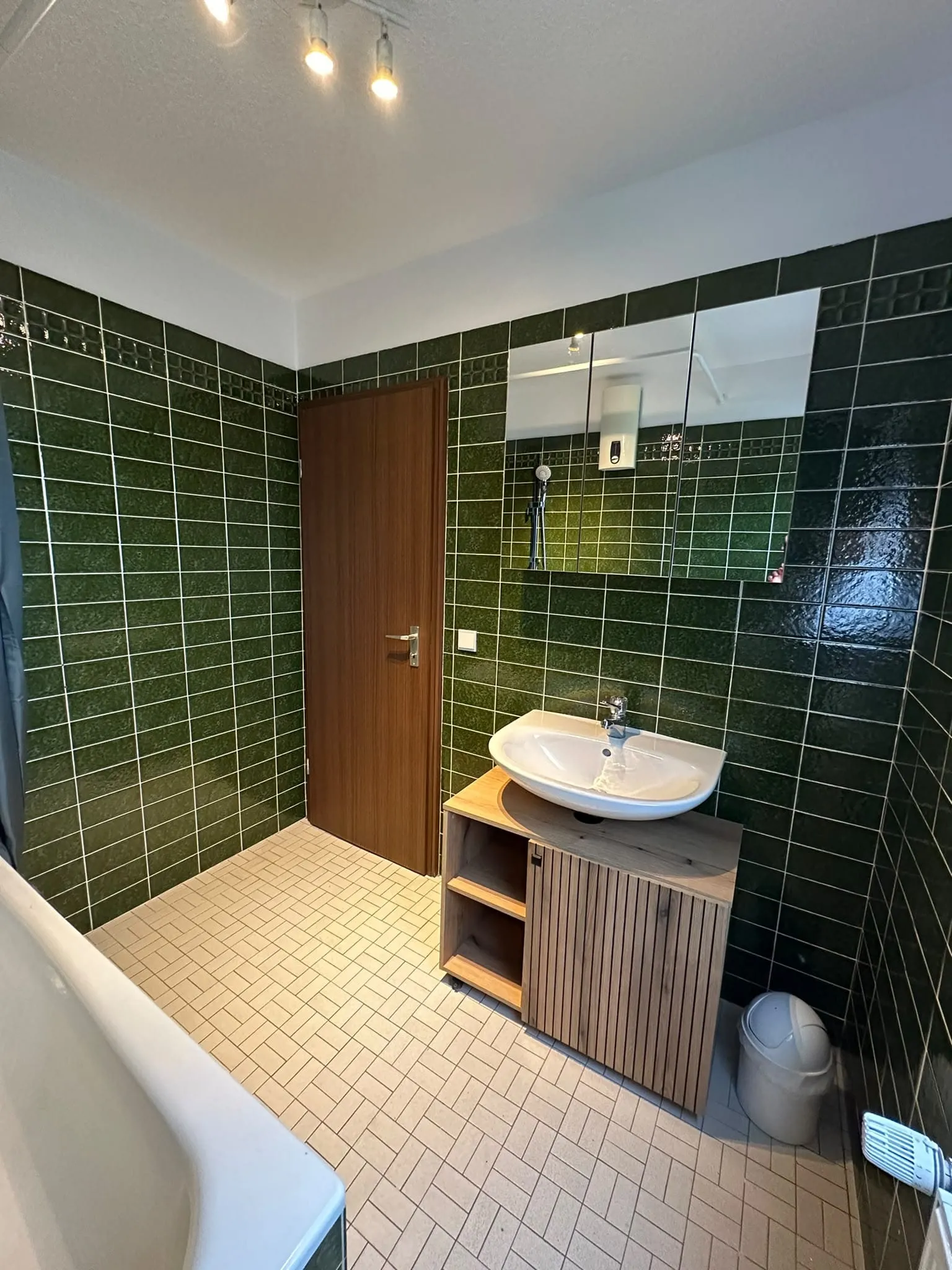 Badezimmer mit Waschtisch, Spiegel und grünen Wandfliesen