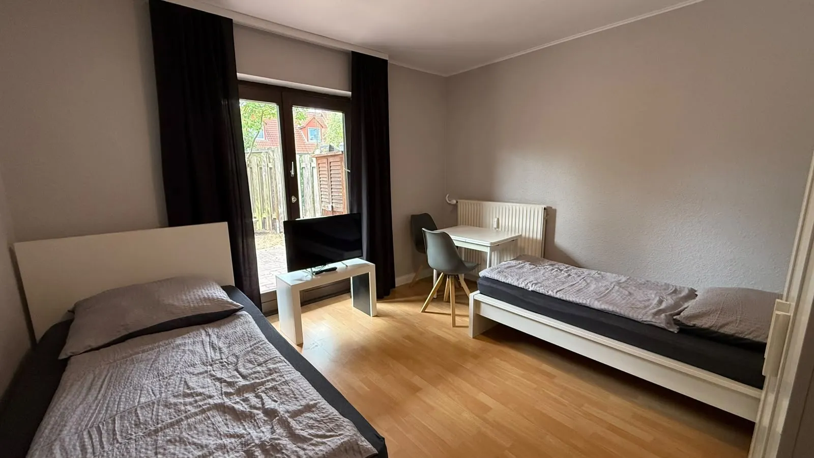 Zimmer mit zwei Betten, Fernseher, Tisch und Zugang zur Terrasse