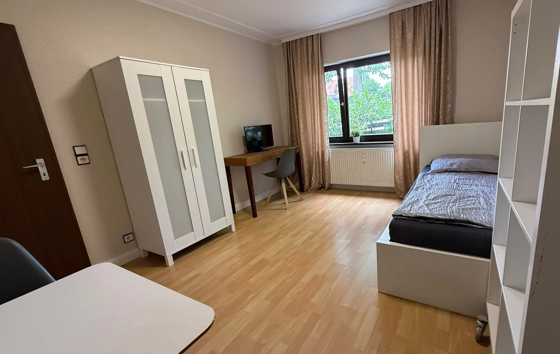Übersicht eines Zimmers mit Schrank, Schreibtisch und Bett